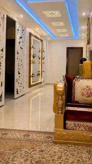A luxurious room with a golden sofa, a large mirror, and a decorative ceiling.