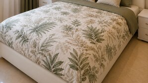 A bedroom with a large bed, a headboard, bedside tables, and a window with curtains.