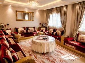 A luxurious living room with a round coffee table, plush red sofas, and a large mirror on the wall.