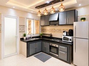 A modern kitchen with dark cabinets, a gas stove, a microwave, and a refrigerator.