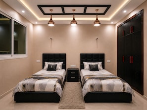 A bedroom with two beds, a large wardrobe, and recessed ceiling lighting.
