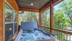 A hot tub on a wooden deck with a view of trees.