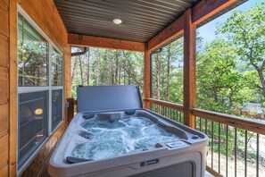 A hot tub on a wooden deck with a view of trees.