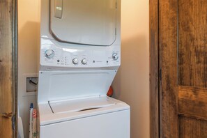 A front-loading washing machine with control panel, located in a room with wooden doors and a white wall.