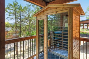 A wooden cabin with a balcony, surrounded by trees.