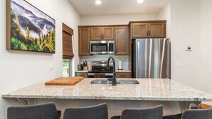 A modern kitchen with granite countertops, stainless steel appliances, and wooden cabinets.