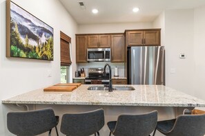 A modern kitchen with granite countertops, stainless steel appliances, and wooden cabinets.