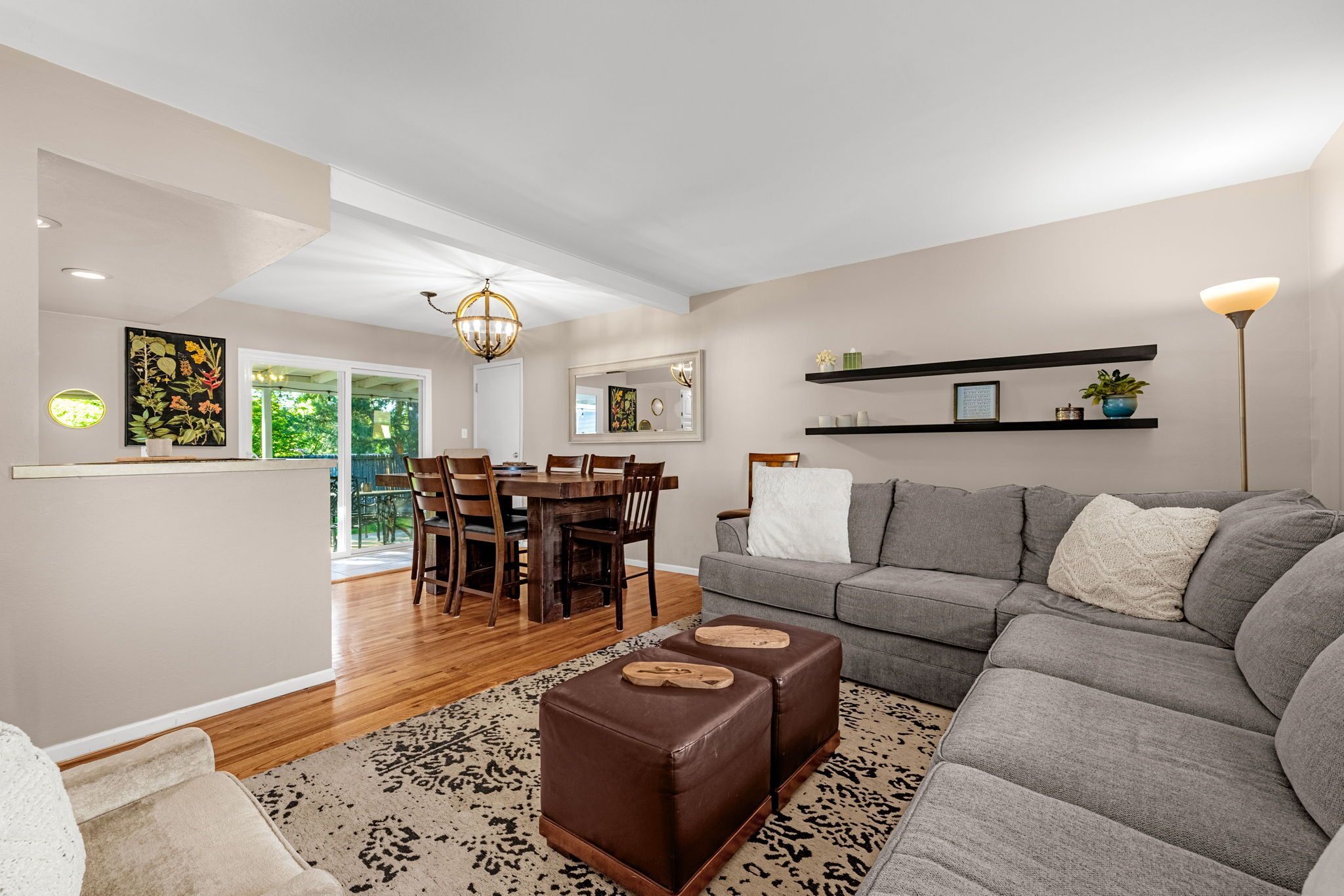 A modern living room with a grey sofa, wooden dining table, and a patterned rug.