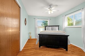 A bedroom with a bed, a ceiling fan, a window with blinds, and a wooden floor. - Garden of the Gods Cottage-4B/3b Pioneer Park (Colorado Springs)