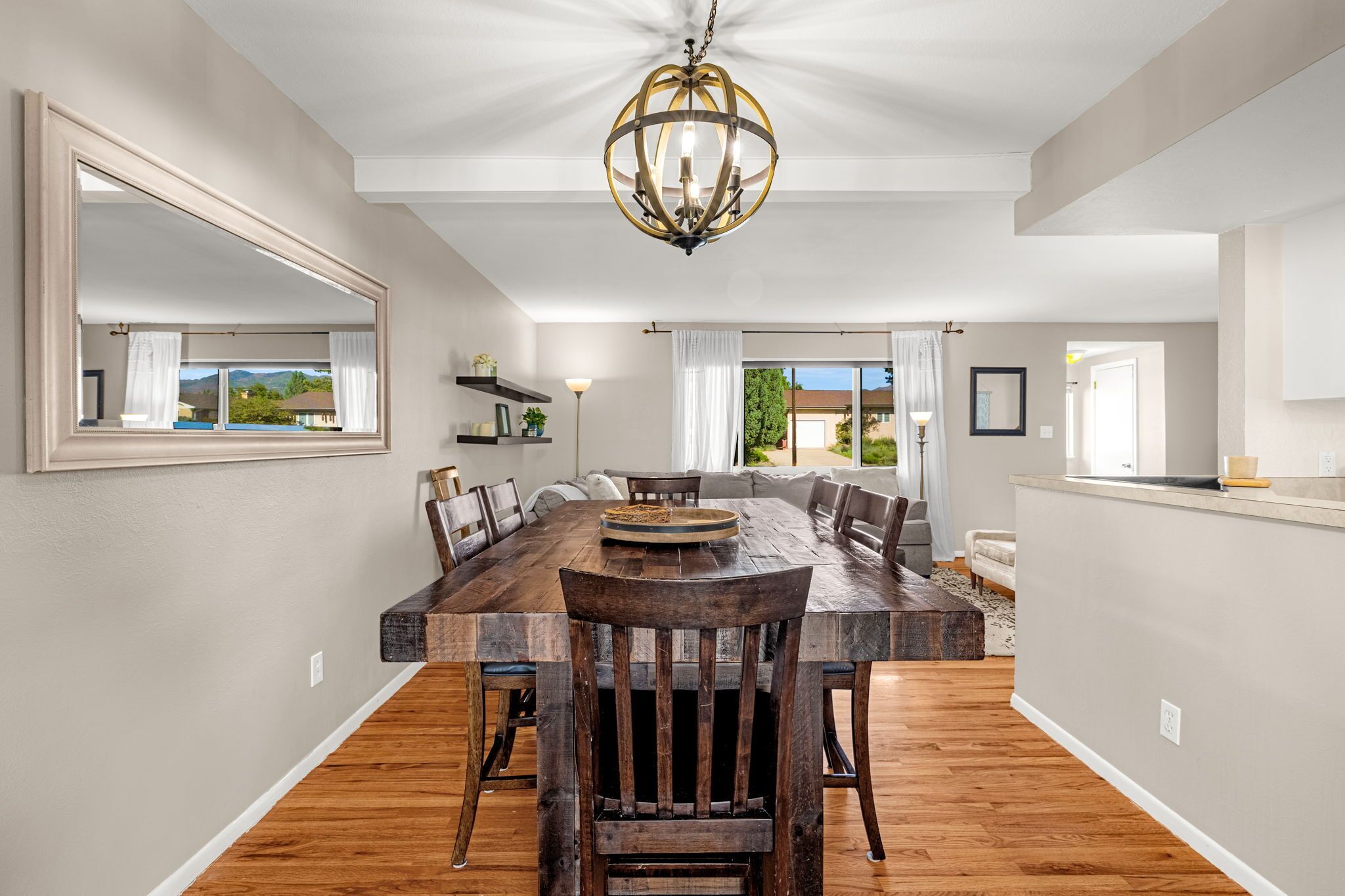 A spacious dining area with a large wooden table, multiple chairs, and a chandelier.