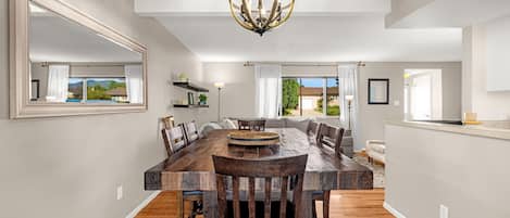 A spacious dining area with a large wooden table, multiple chairs, and a chandelier.