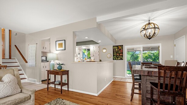 A spacious living area with a wooden floor, a dining table with chairs, a kitchen with white cabinets, and a staircase. - Garden of the Gods Cottage-4B/3b Pioneer Park (Colorado Springs)