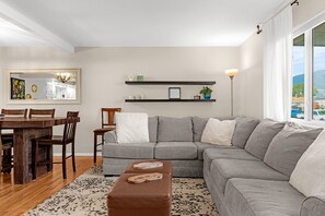 A modern living room with a sectional sofa, a dining table with chairs, a coffee table, and a large window with a view. - Garden of the Gods Cottage-4B/3b Pioneer Park (Colorado Springs)