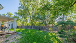 A backyard with a covered patio, a wooden fence, and a lawn. - Garden of the Gods Cottage-4B/3b Pioneer Park (Colorado Springs)
