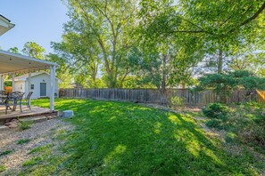 A backyard with a covered patio, a wooden fence, and a lawn. - Garden of the Gods Cottage-4B/3b Pioneer Park (Colorado Springs)