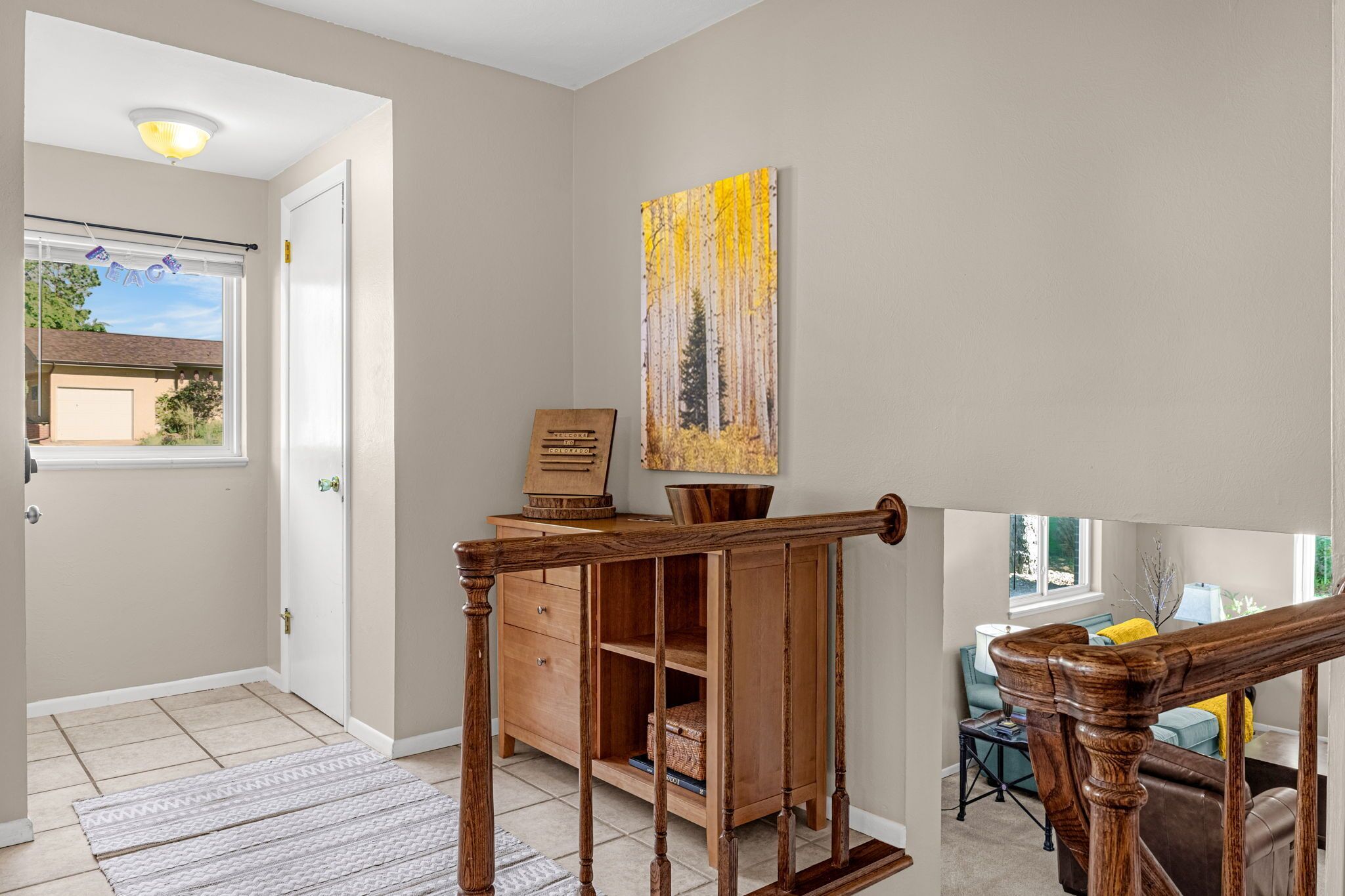 A hallway with a wooden bench, a door, and a painting on the wall.
