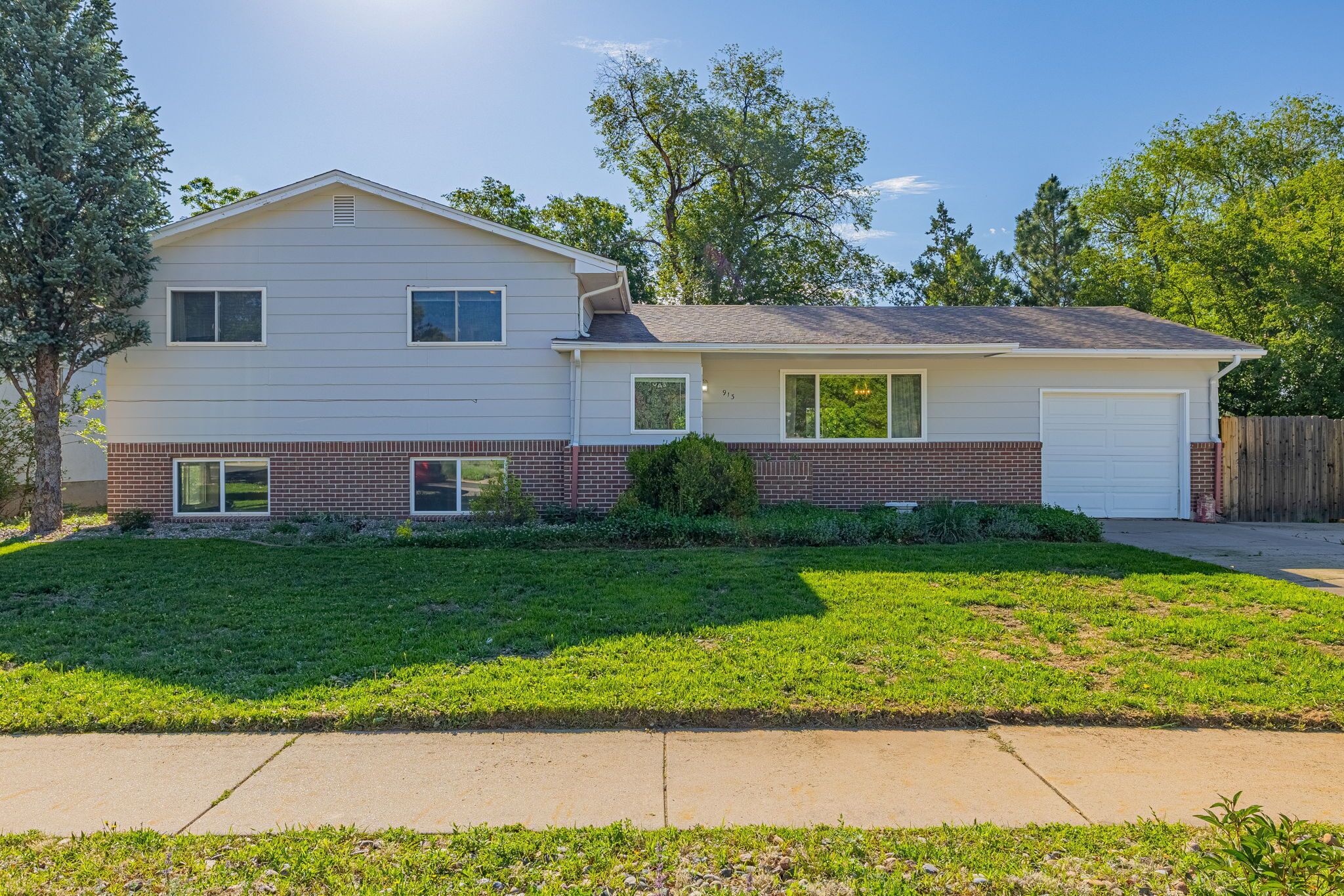 A two-story house with a garage, a well-maintained lawn, and a wooden fence.