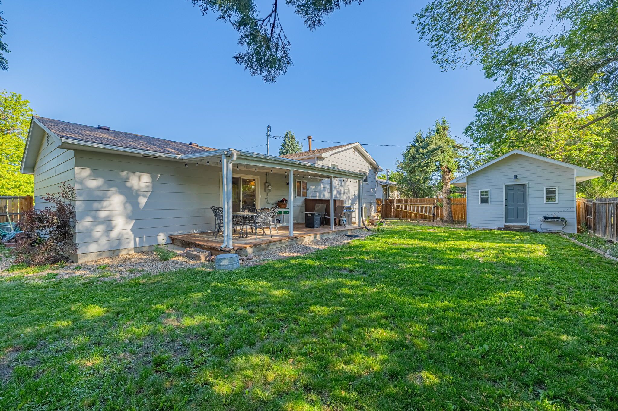 A residential property with a covered patio, a small detached garage, and a well-maintained lawn.