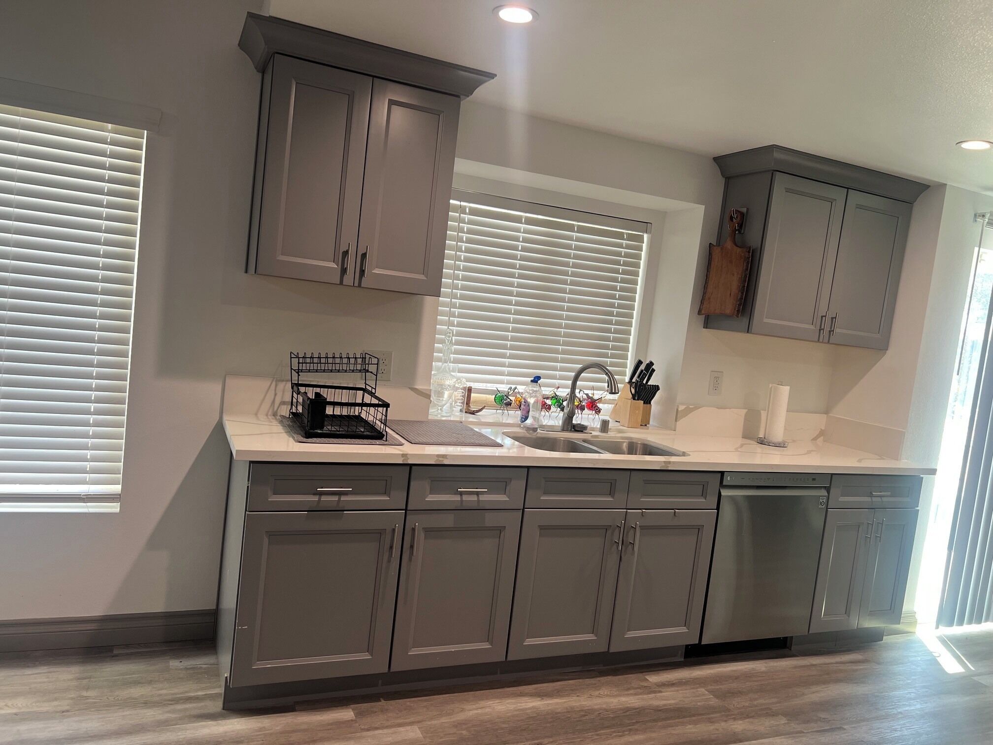 A modern kitchen with grey cabinets, a stainless steel sink, and a built-in dishwasher.