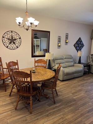 A dining area with a wooden table and chairs, a chandelier, and a mirror on the wall. - Spacious 3-bedroom condo with pool/fitness center in lovely Fort Myers (Fort Myers)