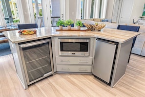 Eine moderne Küche mit integriertem Mikrowellenherd, einem Kühlschrank und einer Arbeitsplatte mit einer Obstplatte.