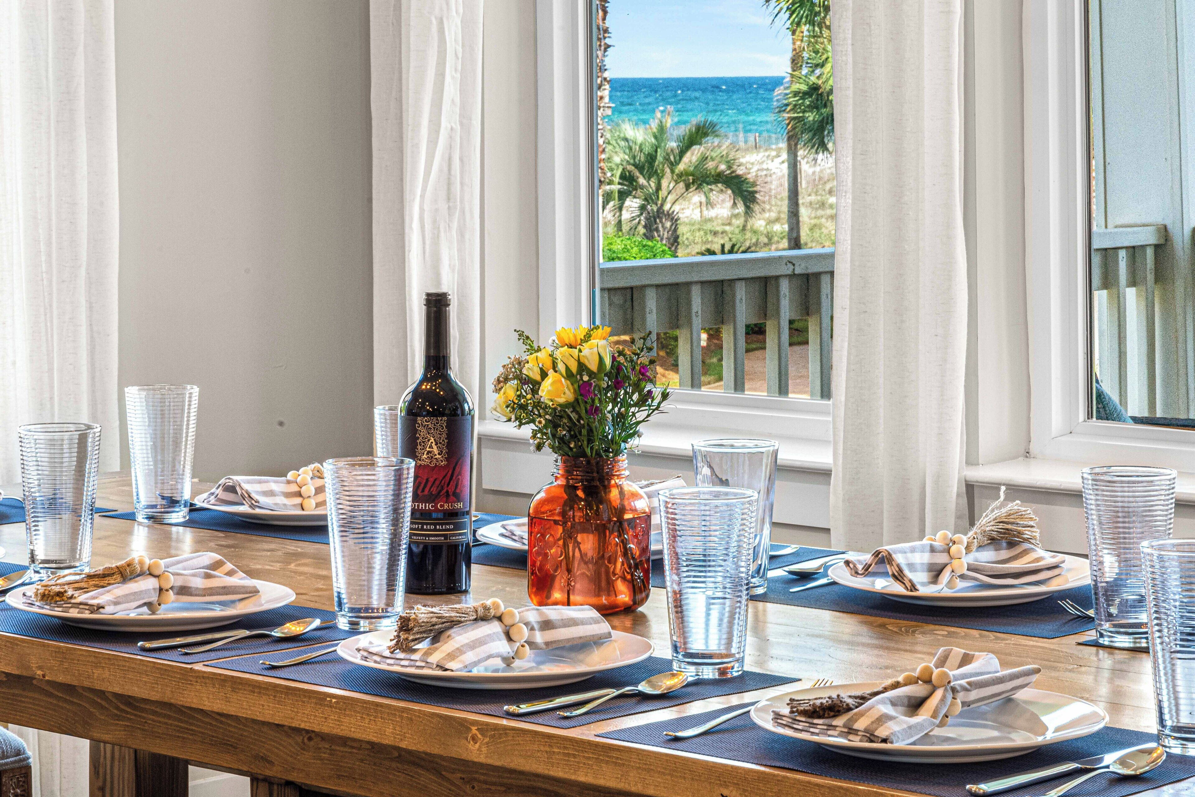 A dining table set with plates, cutlery, and glasses, with a bottle and a vase of flowers on the table.
