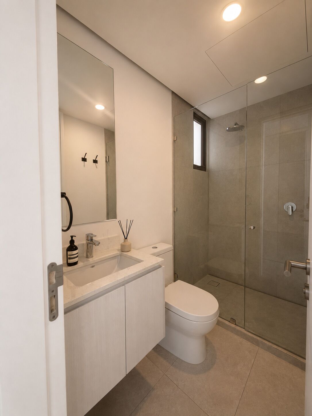 Un bagno moderno con cabina doccia in vetro, un lavandino bianco e un water.