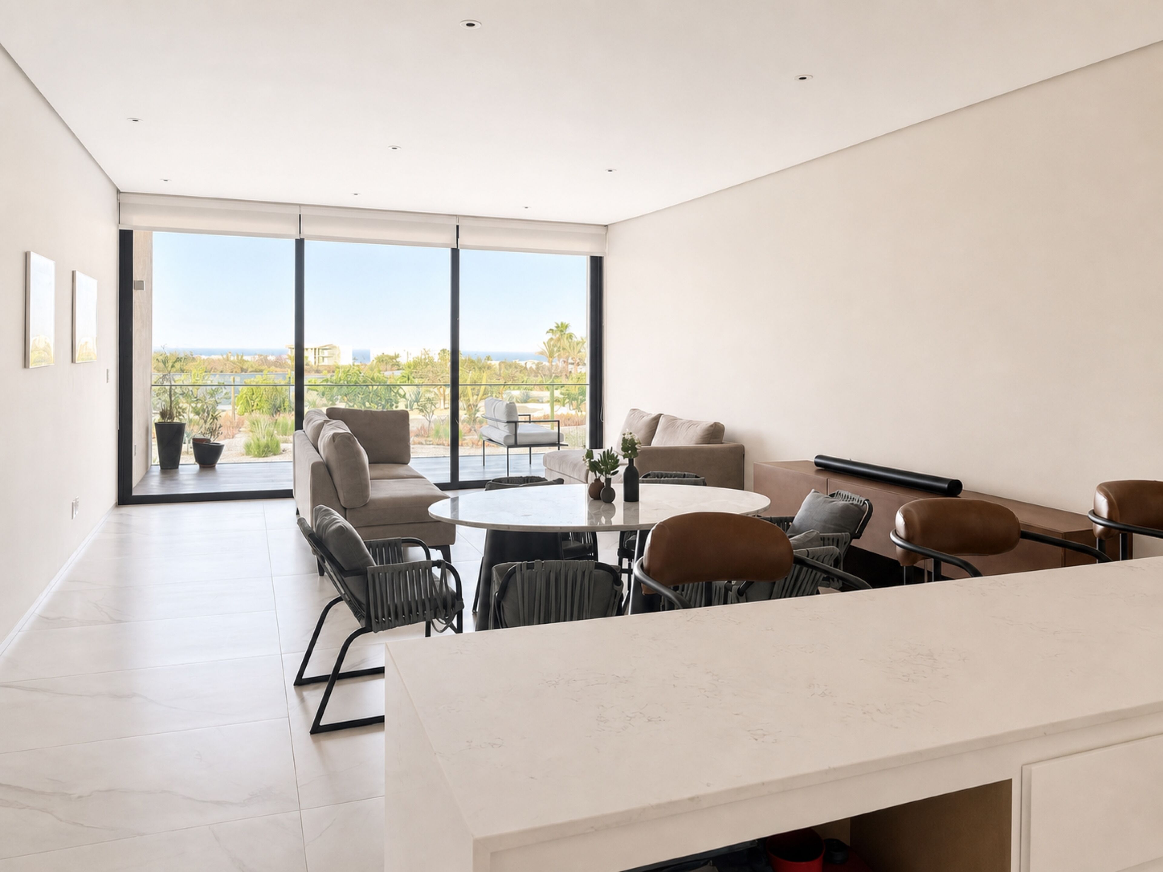 Un interior moderno con comedor, asientos y grandes ventanales que ofrecen vistas.