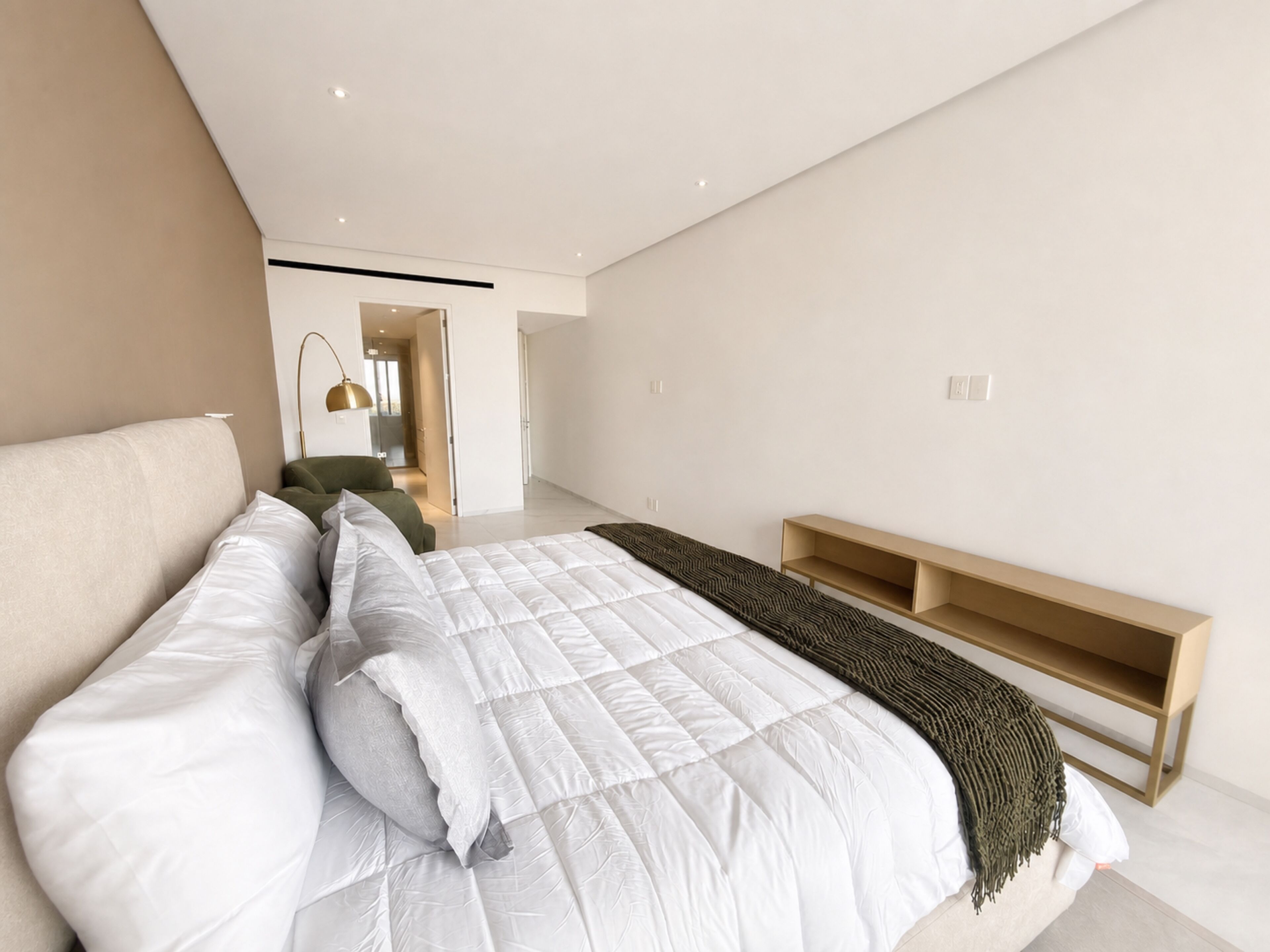 A modern bedroom with a large bed, a bedside table, and a built-in bench.