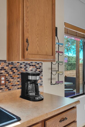 A kitchen with wooden cabinets, a coffee maker, and a tiled backsplash. - Spacious Central Tucson Home • Garage & Dogs OK (Tucson)