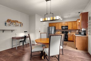 A modern kitchen with wooden cabinets, a black refrigerator, and a microwave.