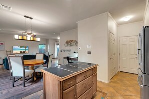 A modern kitchen with a dining area, wooden cabinetry, and a built-in island. - Spacious Central Tucson Home • Garage & Dogs OK (Tucson)