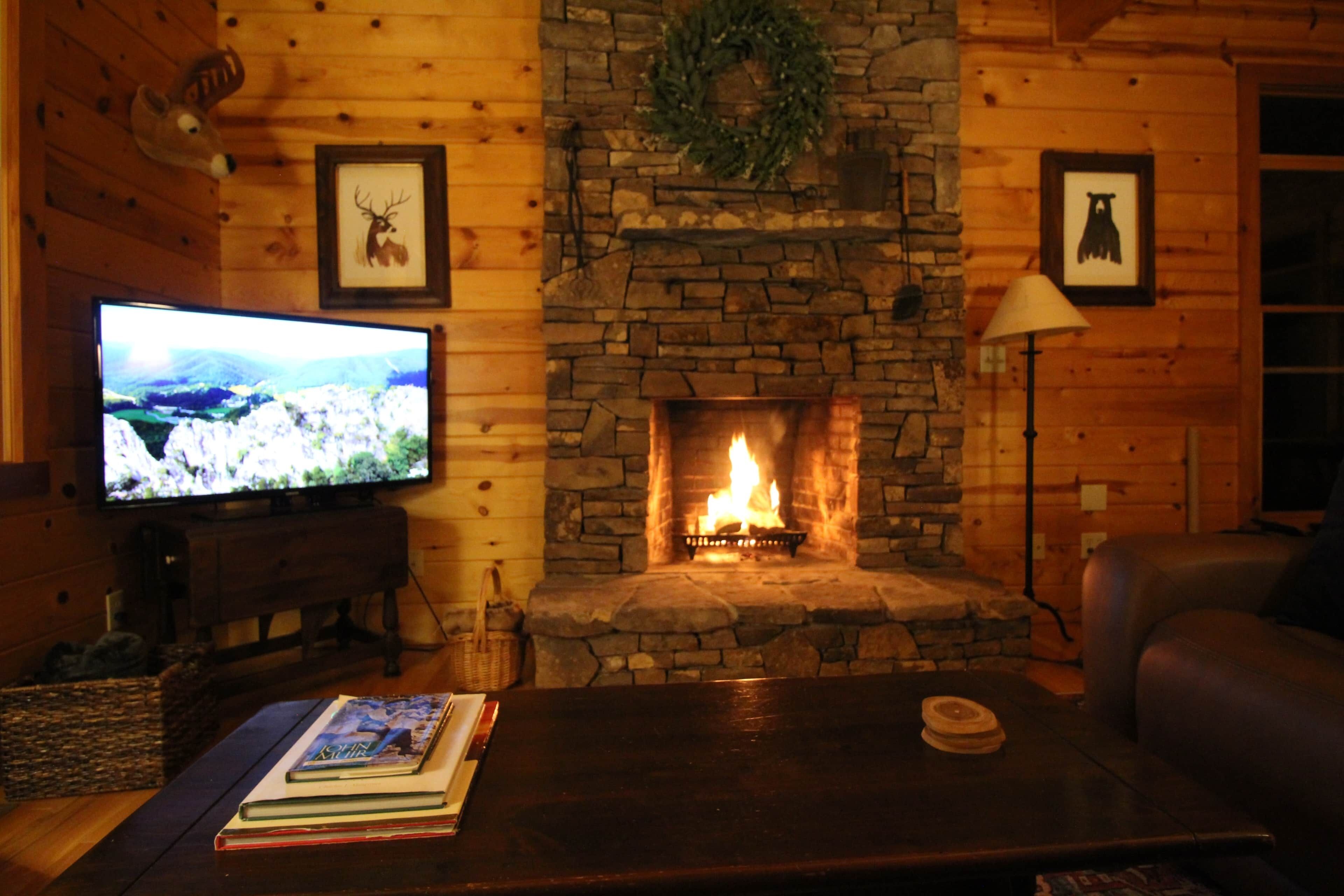 Ein gemütliches Wohnzimmer mit Kamin aus Stein, einem Fernseher und einer Ledersofa.