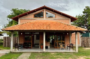 Une maison à deux étages, avec un toit en tuiles, un patio couvert doté de meubles d’extérieur et une façade en briques.