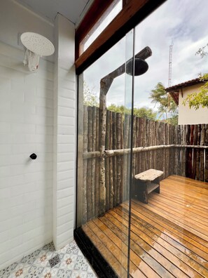 A wooden deck with a bench, a glass door leading outside, and a white tiled wall.