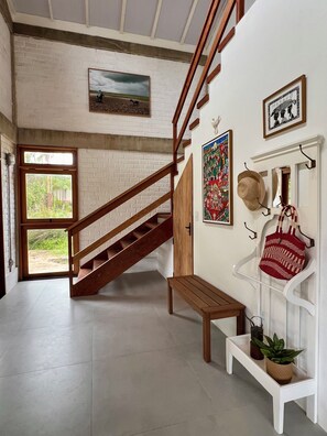 A staircase with wooden railings, a bench, a wall-mounted hat rack, and a potted plant.