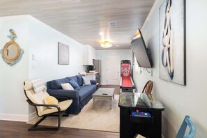 A living room with a sofa, coffee table, and a gaming console. - 8 Bed Oceanfront w Pool/Spa, Private Beach Access! (Nags Head)