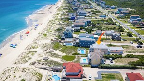Zona residencial costera con propiedades frente al mar, piscina y playa con sombrillas.