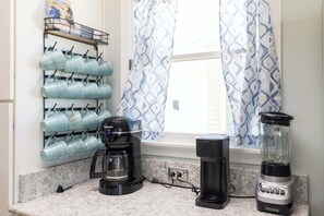 A kitchen with a coffee maker, a blender, and a rack of mugs. - 8 Bed Oceanfront w Pool/Spa, Private Beach Access! (Nags Head)