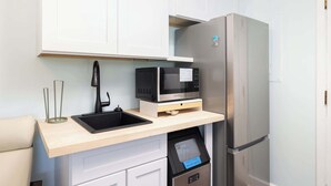 Una cocina compacta con microondas integrado, refrigerador de acero inoxidable y un lavamanos pequeño.
