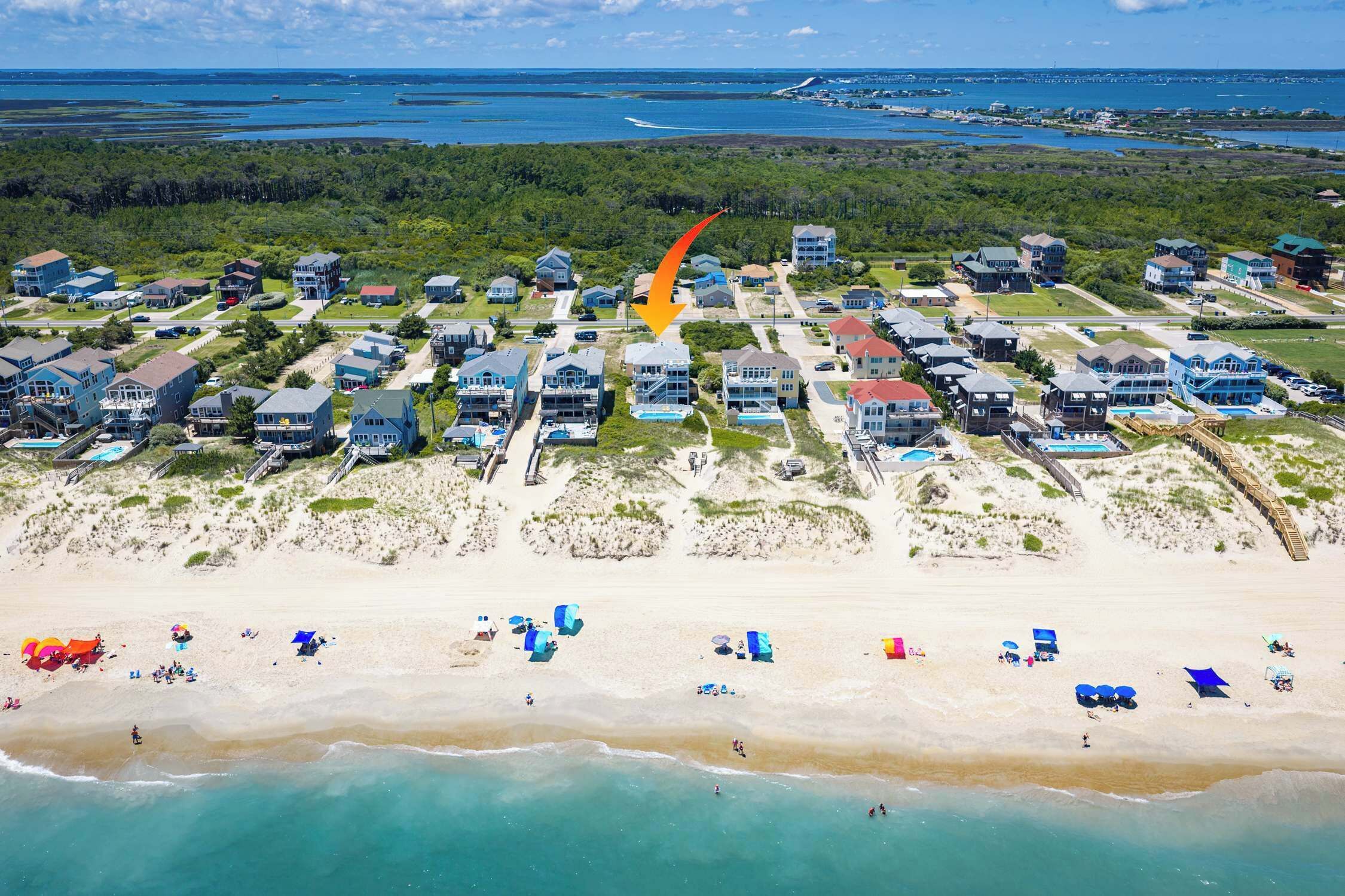 A coastal residential area with beachfront properties, a sandy beach, and a clear view of the ocean.
