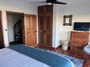 Een slaapkamer met een bed, een kledingkast, een televisie en een trap.