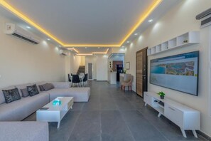 A modern living room with a sofa, coffee table, and TV. There is a staircase leading to another level.