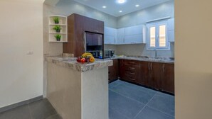 A kitchen with a marble countertop, wooden cabinets, and a built-in refrigerator.