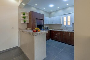 A kitchen with a marble countertop, wooden cabinets, and a built-in refrigerator.