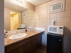 A bathroom with a sink, mirror, microwave, and a small refrigerator. - Good Knight Inn Motel  (Lloydminster)