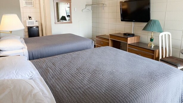 Een hotelkamer met twee bedden, een televisie, een bureau en een stoel.