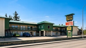Een motel met een groene gevel, een bord met daarop The Good Knight Inn, en een zichtbaar bord met vrije kamers.