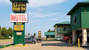 Un motel con fachada verde, un letrero que indica habitación disponible y un cartel que dice The Good Knight Inn.