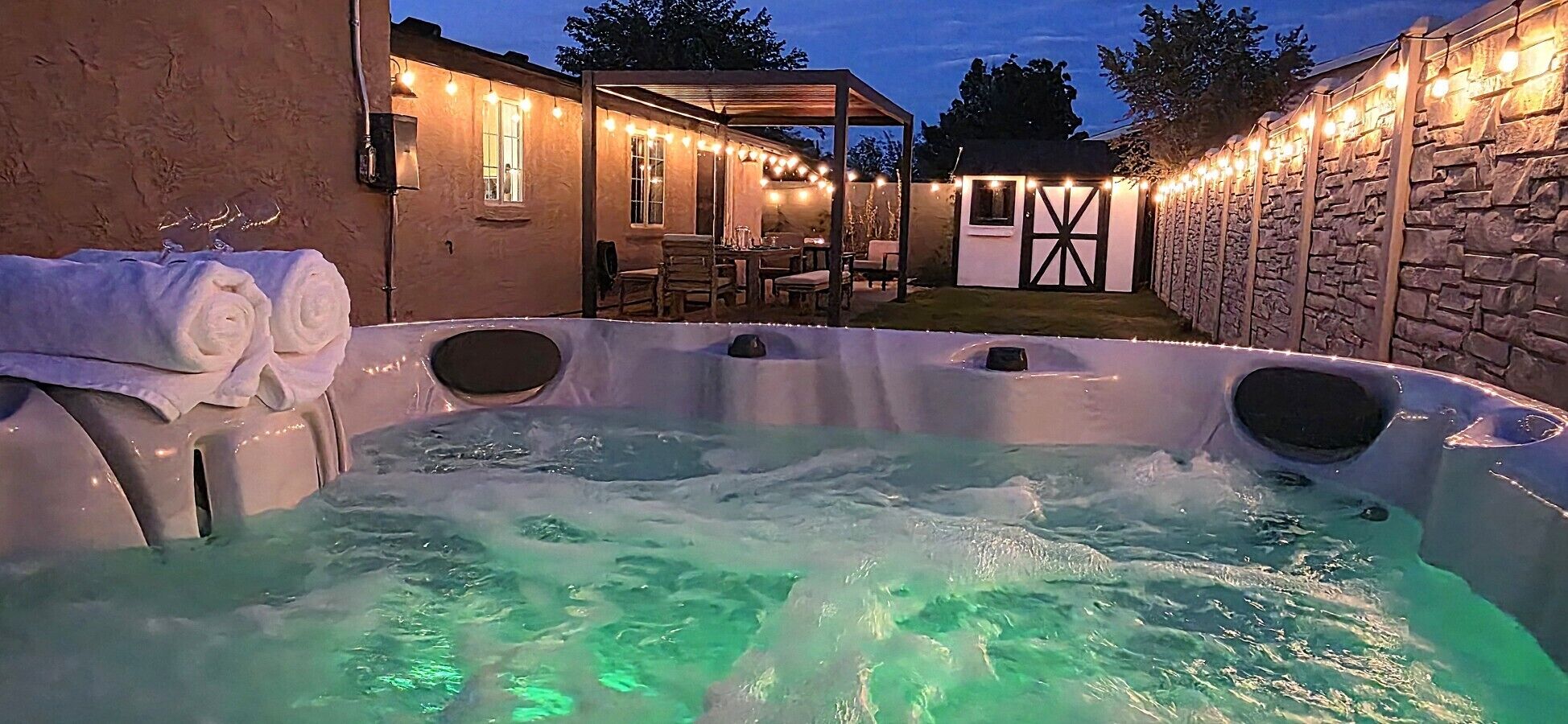 Ein Whirlpool mit Steinwand und überdachter Terrasse.